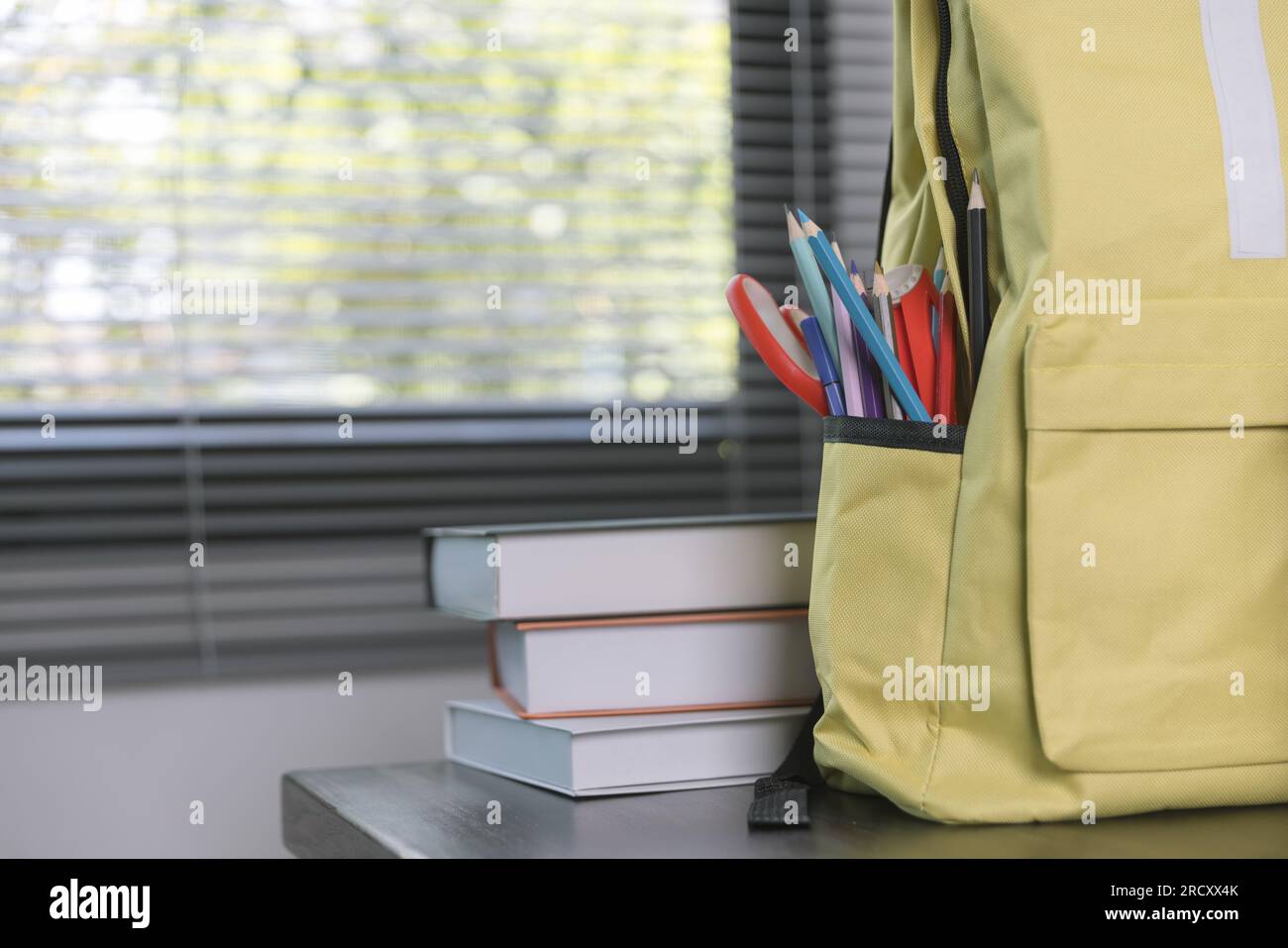 Forniture scolastiche su un tavolo di legno in interni caldi, libri scolastici sul tavolo, concetto educativo. Foto Stock