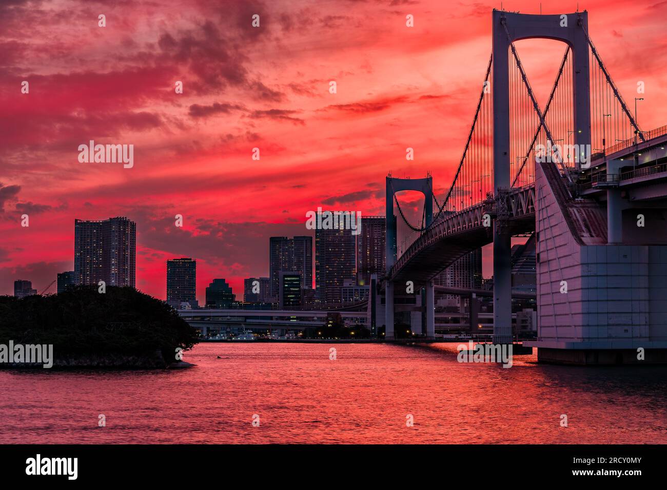 Un cielo vivace e colorato al tramonto al crepuscolo dietro i grattacieli di Tokyo e il Rainbow Bridge Foto Stock