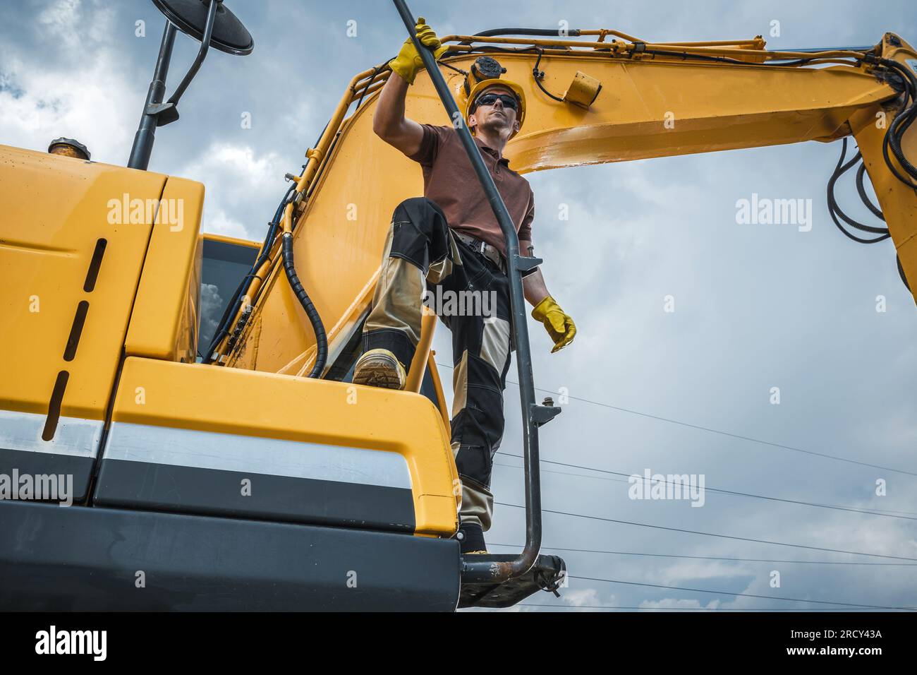 Macchina scavatrice di terra e suo proprietario. Tema del lavoro dell'escavatore. Foto Stock