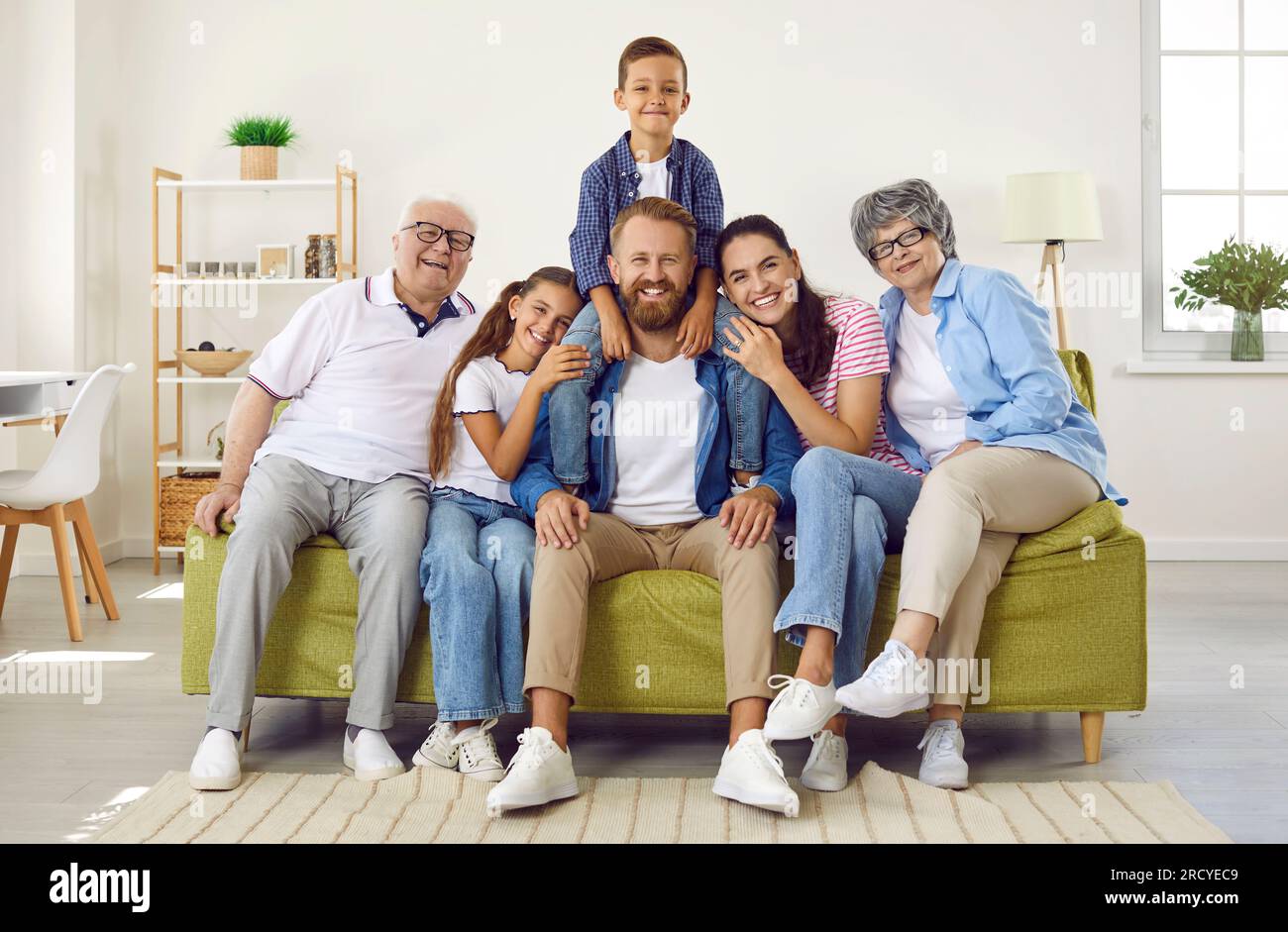 Ritratto di una famiglia felice, cordiale e amorevole di tre generazioni seduta insieme sul divano a casa Foto Stock