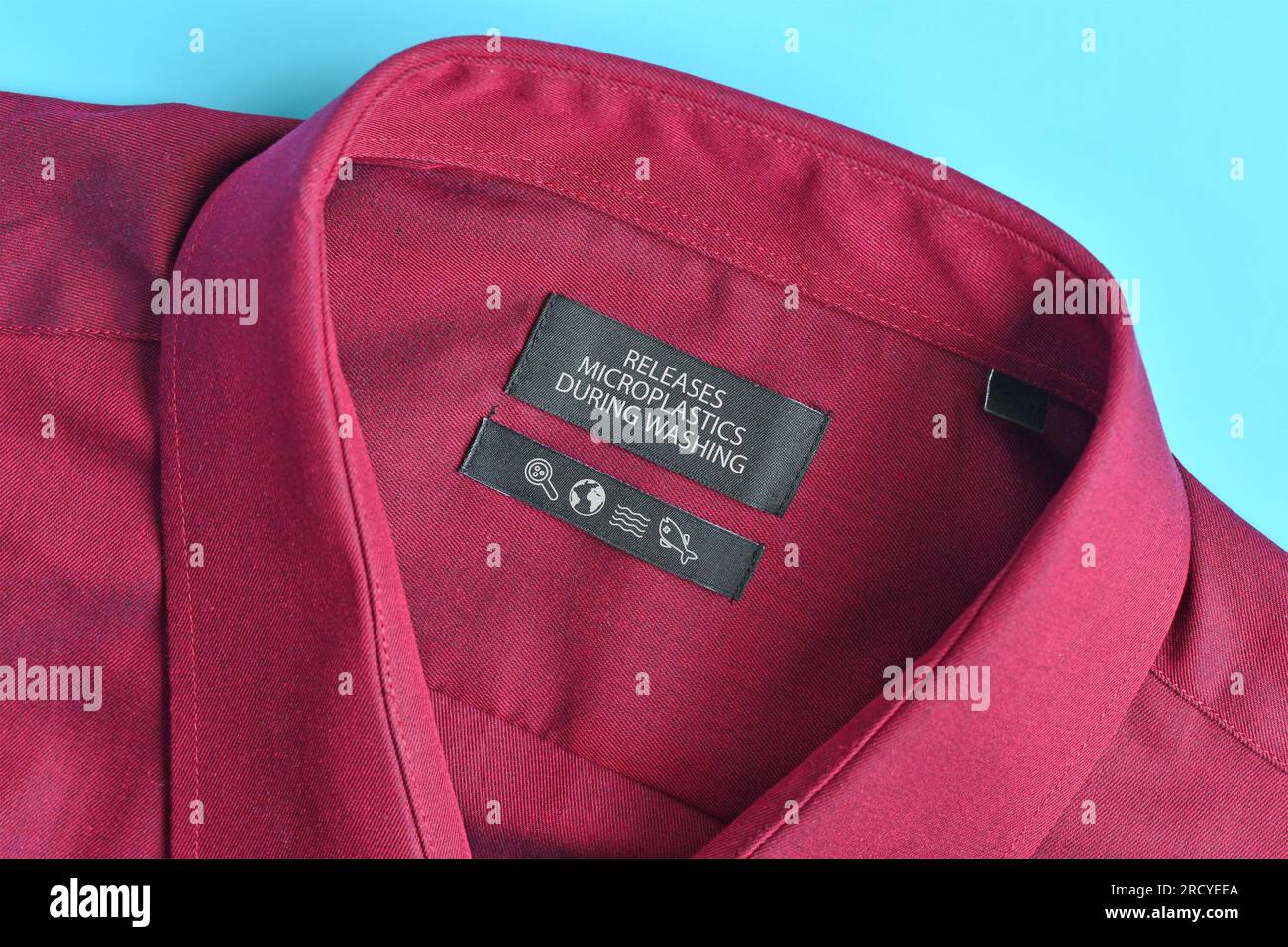 Camicia con etichetta "rilascia microplastiche durante il lavaggio". Concetto per il problema dell'inquinamento delle fibre sintetiche degli indumenti Foto Stock