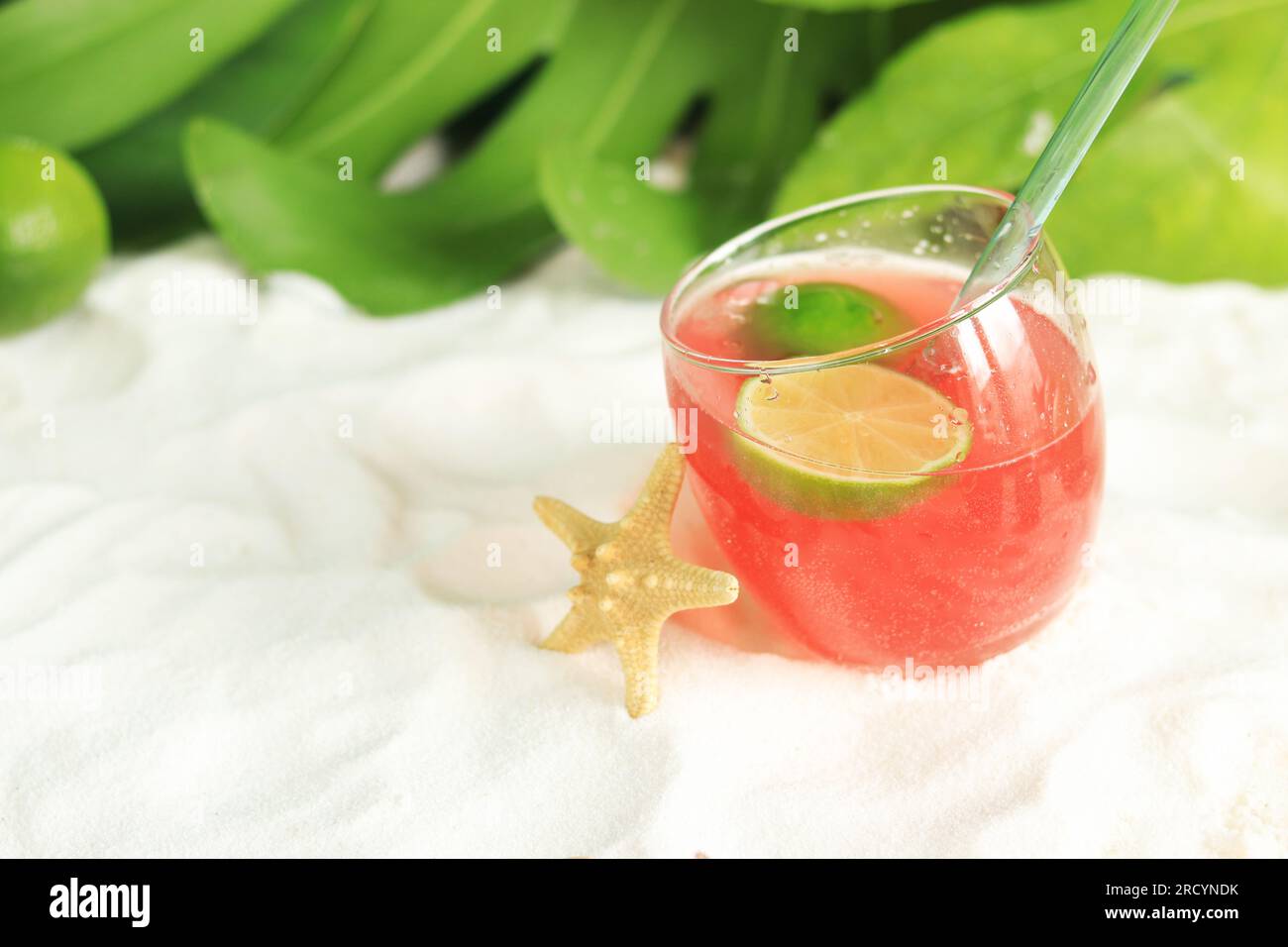 Cocktail rosa sulla sabbia. Vacanze estive, concetto di resort. Drink rinfrescante sulla spiaggia, stelle marine vicino al bicchiere. Messa a fuoco selettiva Foto Stock