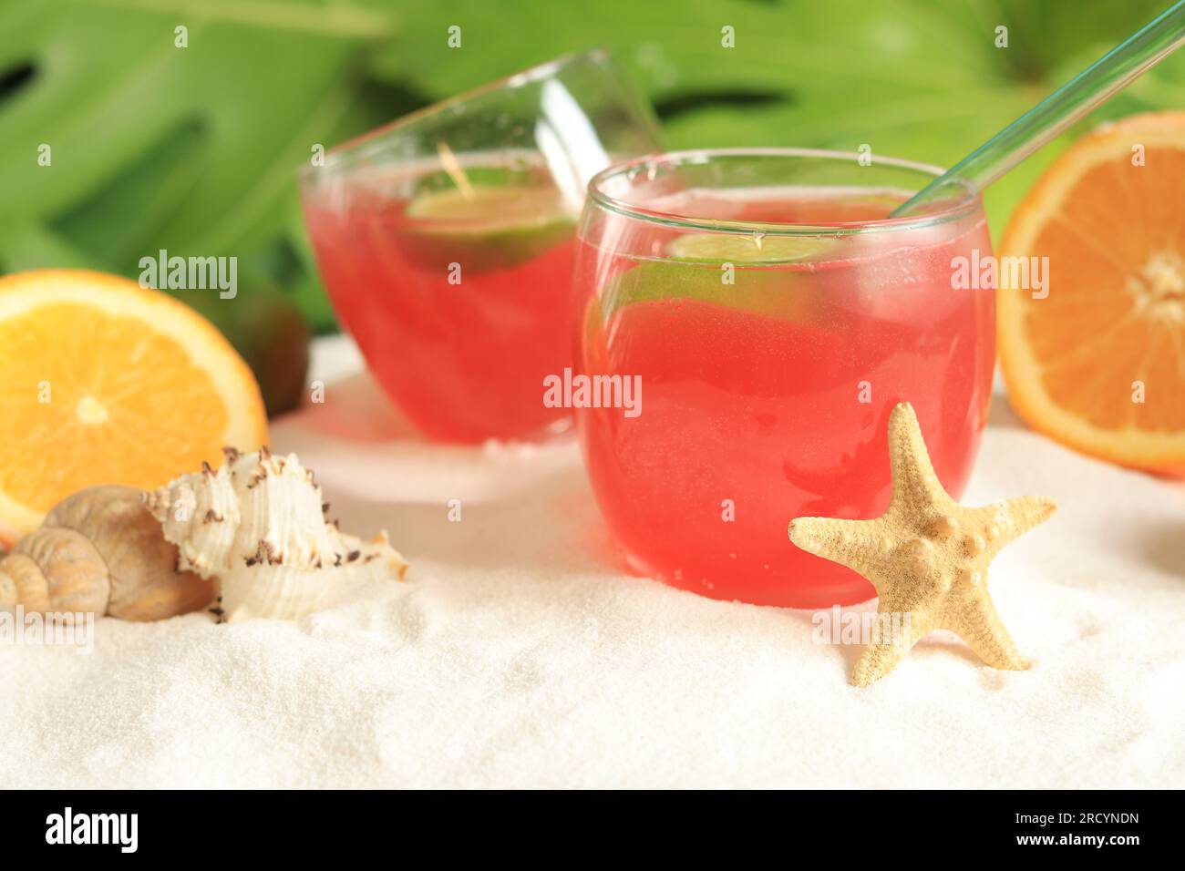 Cocktail alcolico di colore rosa vicino a frutti tropicali. Drink fresco sulla spiaggia. Messa a fuoco selettiva Foto Stock