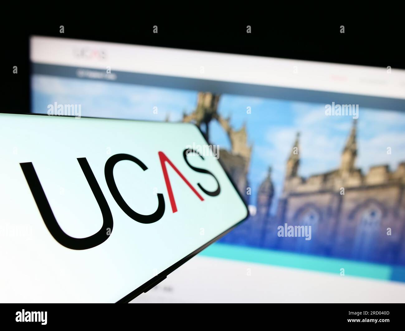 Smartphone con logo UCAS (Universities and Colleges Admissions Service) sullo schermo davanti al sito Web. Mettere a fuoco il display centrale sinistro del telefono. Foto Stock
