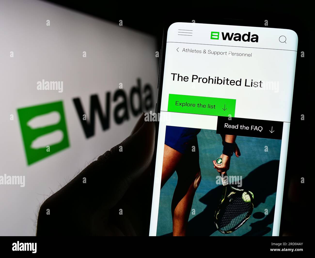 Persona che tiene uno smartphone con pagina web dell'organizzazione World Anti-doping Agency (WADA) sullo schermo con logo. Concentrarsi sul centro del display del telefono. Foto Stock