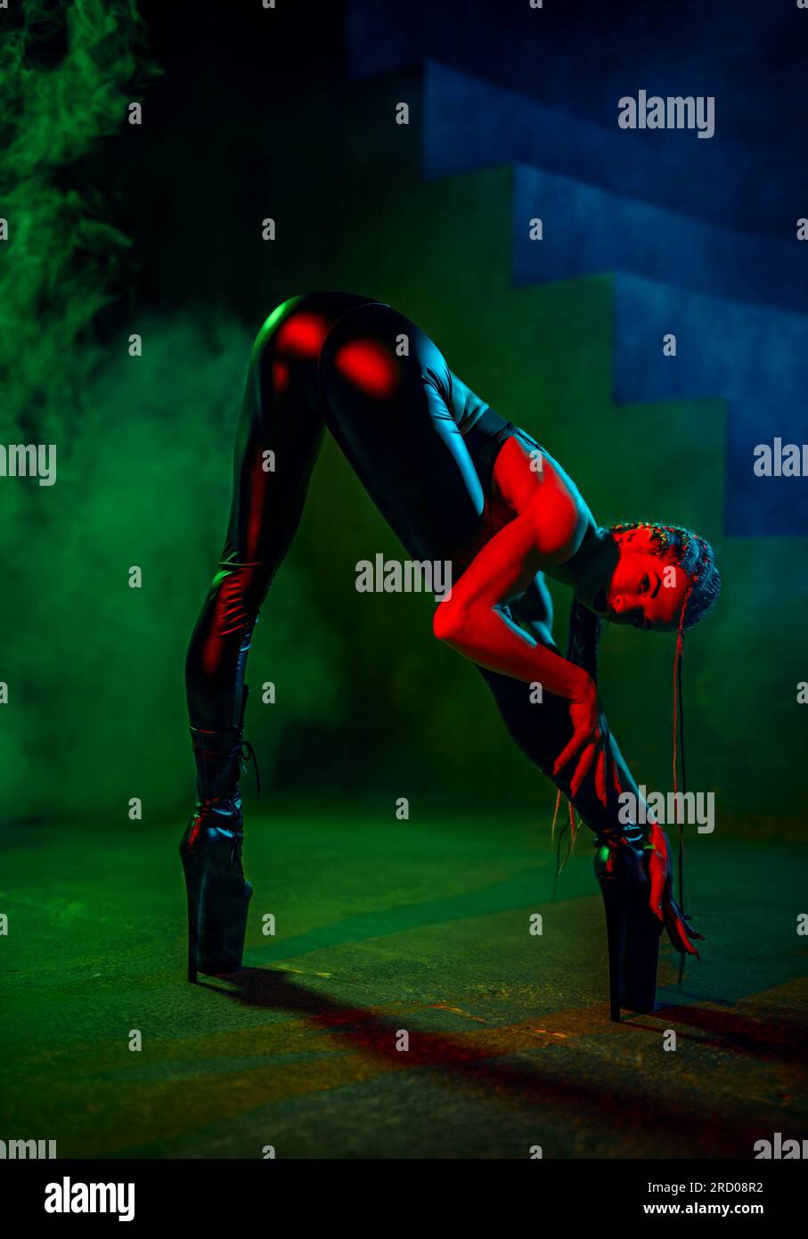 Giovane ballerina in posa con pantaloni in pelle nera in studio scuro con fumo Foto Stock