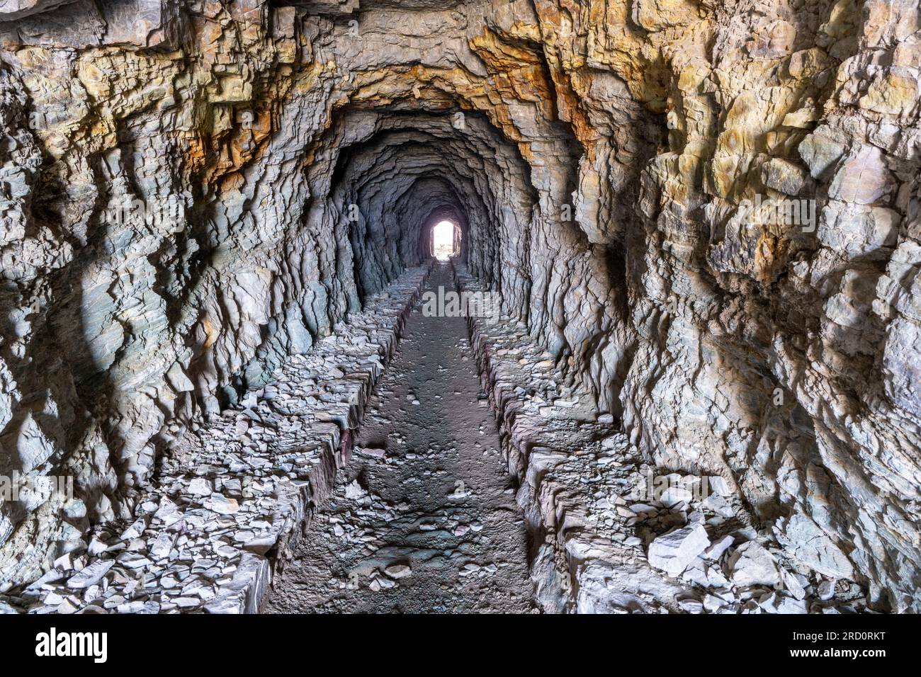 La luce naturale ha illuminato un tunnel pedonale che attraversa la roccia rossa di argillite e quarzite, il tunnel di Ptarmigan, il Glacier National Park, Montana Foto Stock