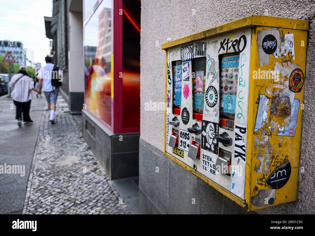 Berlino, Germania. 15 luglio 2023. Un distributore automatico di gomme da masticare è appeso alla facciata di un edificio in Friedrichstraße 218 a Kreuzberg. Anche se i nostalgici distributori automatici sono ora molto meno popolari di circa 50 anni fa, hanno ancora una base di fan. (A dpa "Old Love does not Rust - Why chewing gum vending machines are so nostalgic") credito: Jens Kalaene/dpa/Alamy Live News Foto Stock