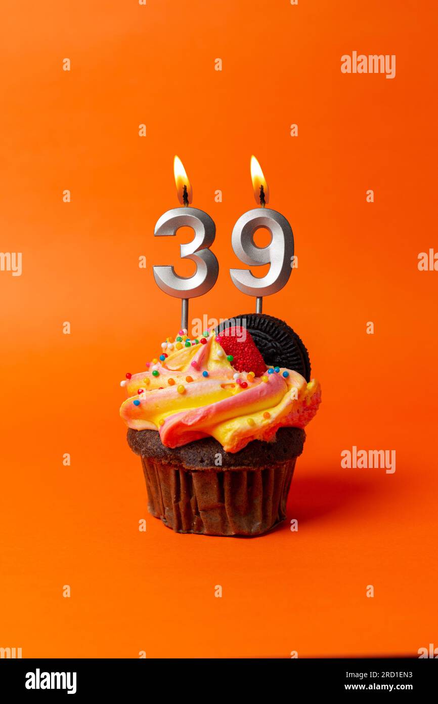 torta di compleanno con numero 39 - cupcake su sfondo arancione con candele di compleanno Foto Stock