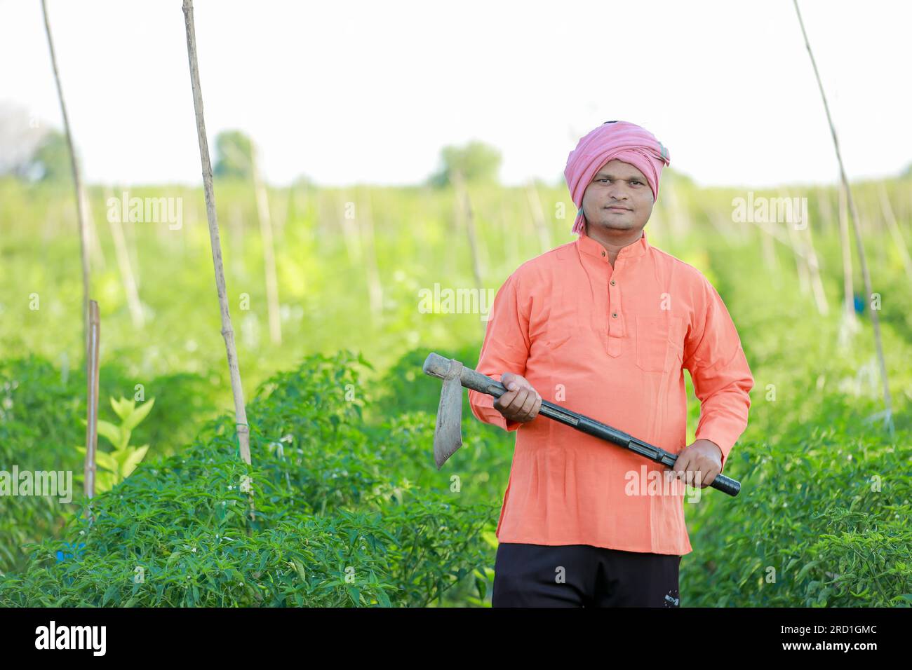 Felice agricoltore indiano, che tiene in mano gli strumenti agricoli Foto Stock