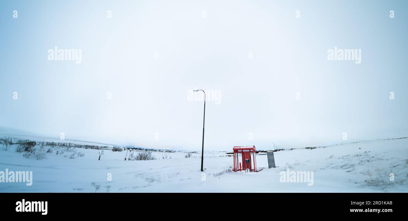 Stazione di ricarica esterna per auto elettriche con tetto rosso completamente circondata dalla neve presso una stazione di servizio in Islanda Foto Stock
