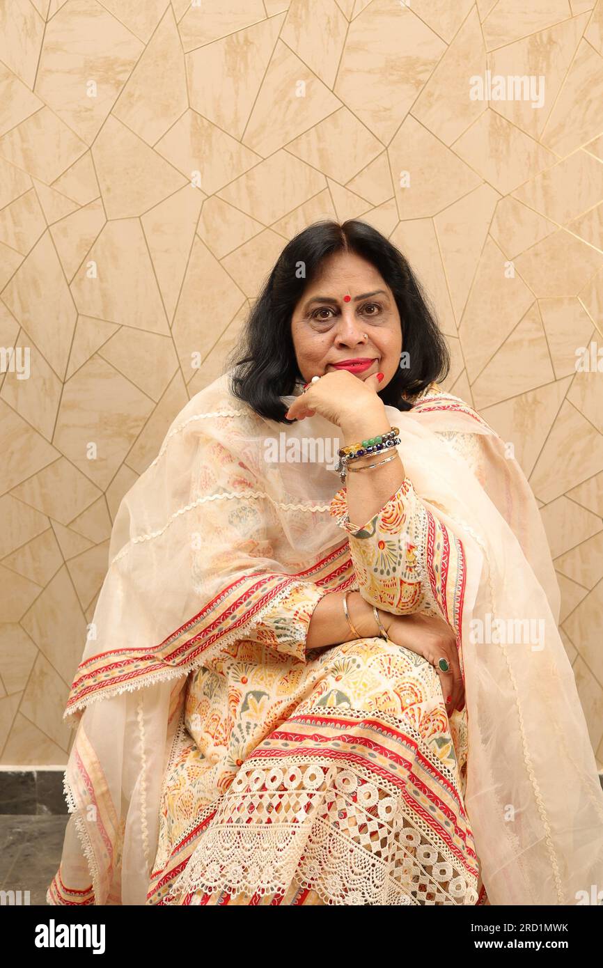 Vecchia signora indiana in piedi con il muro. Parete bianca. Bellissimo e felice ritratto della nonna in piedi contro il muro nel soggiorno arredato di recente. Foto Stock