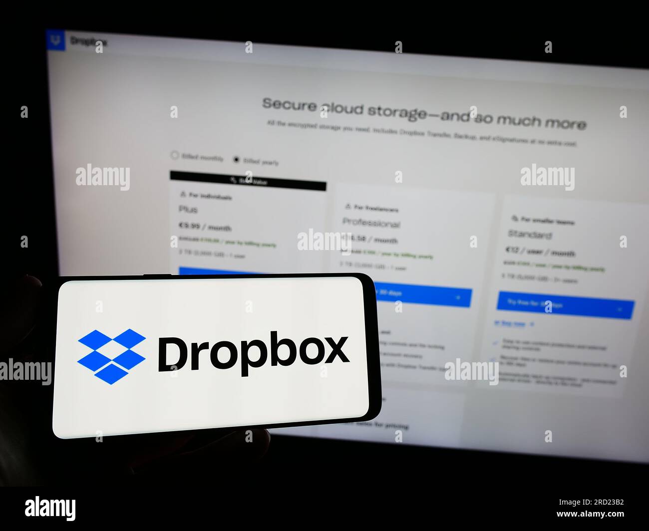 Persona che possiede uno smartphone con il logo della società statunitense di hosting di file Dropbox Inc. Sullo schermo di fronte al sito Web. Concentrarsi sul display del telefono. Foto Stock