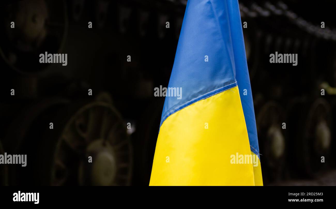 Bandiera nazionale Ucraina, con carro armato da battaglia sullo sfondo. Manifestazione di protesta contro l'invasione della Russia, la guerra in Ucraina. Foto Stock