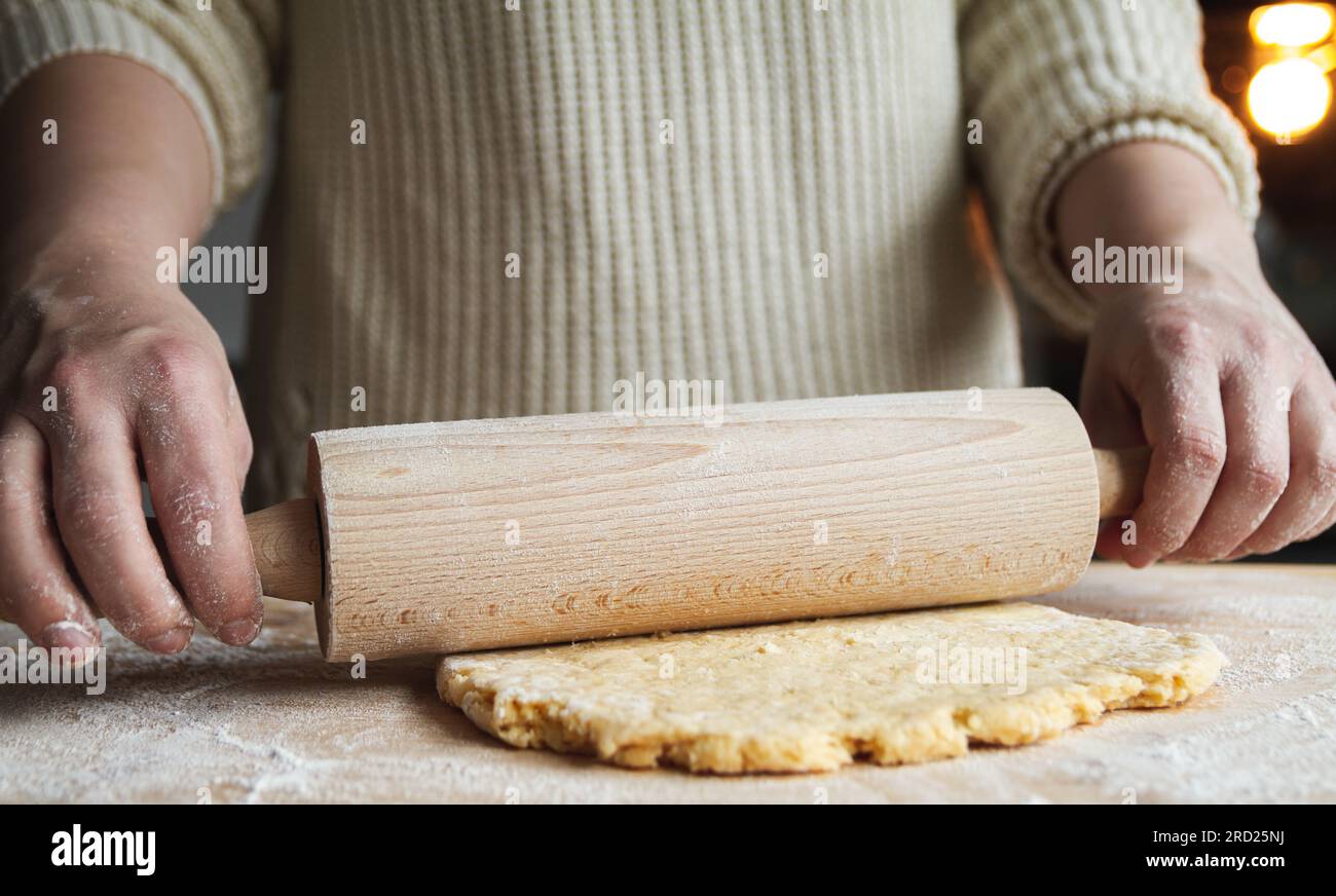Donna che usa il mattarello, prepara l'impasto per pizza, pane, torta fatta in casa o biscotti di Natale. Impasto a mani femminili con spillo. Foto Stock