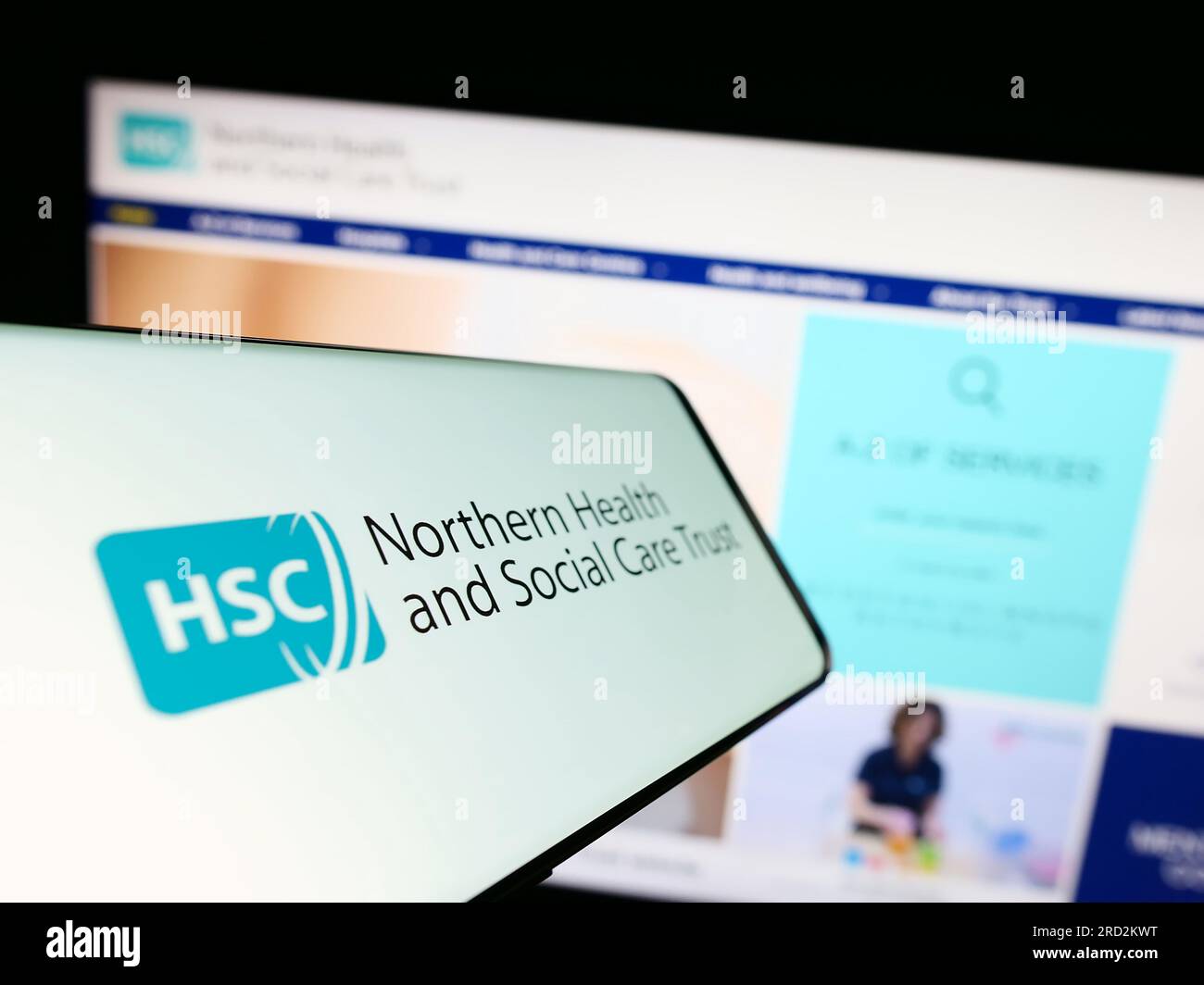 Cellulare con logo di Health and Social Care (HSC) in Irlanda del Nord sullo schermo di fronte al sito web. Mettere a fuoco il display centrale sinistro del telefono. Foto Stock
