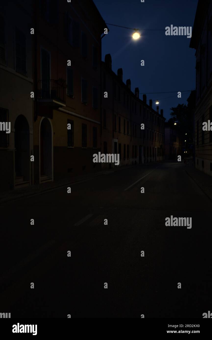 Strada stretta con una lampada a sospensione sopra di essa in una città italiana al crepuscolo Foto Stock