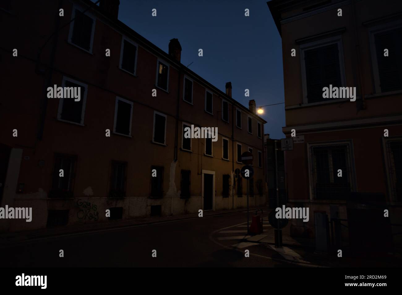 Strada stretta con una lampada a sospensione sopra di essa in una città italiana al crepuscolo Foto Stock