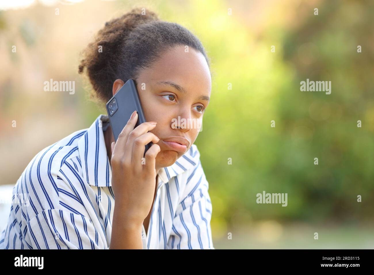 Donna nera impaziente che si lamenta di parlare al telefono in un parco Foto Stock
