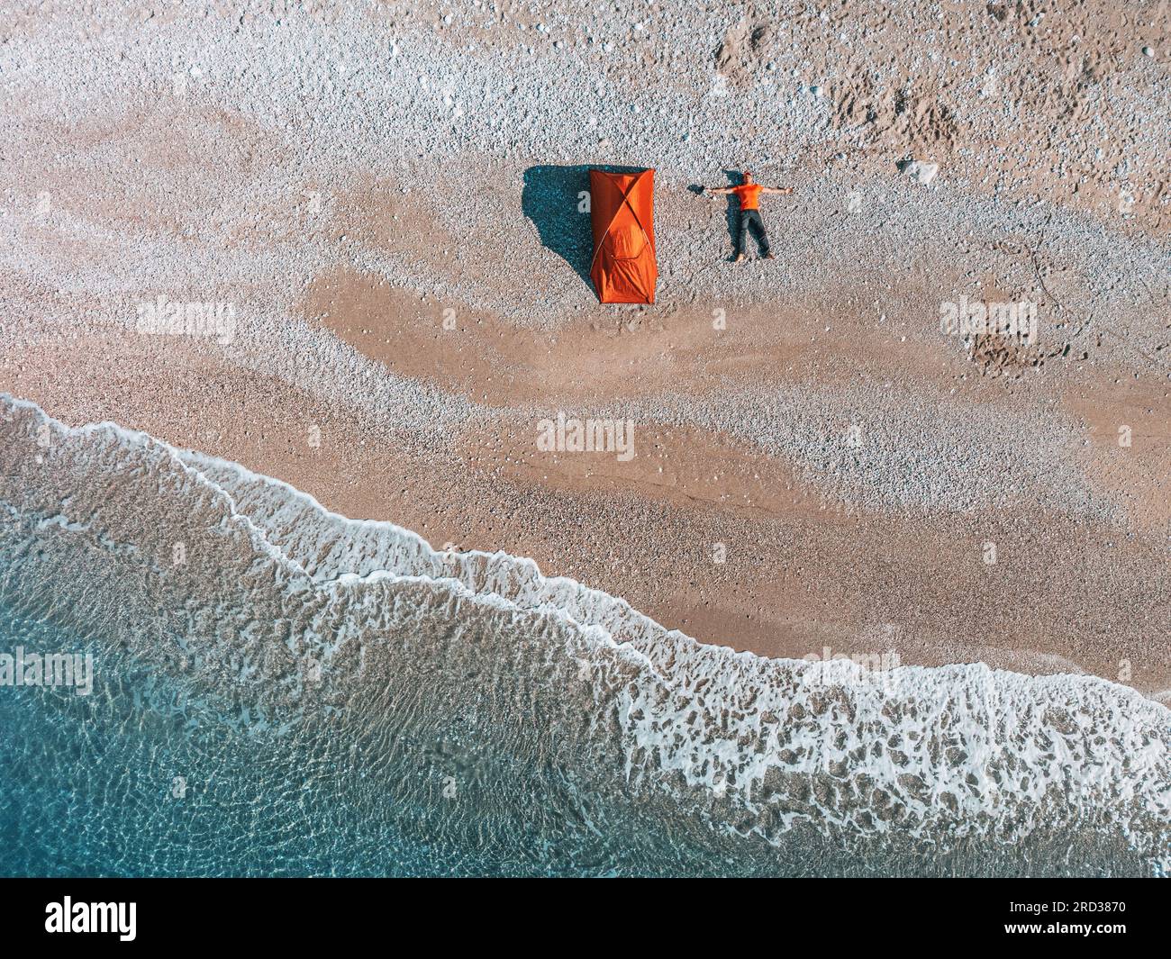 la foto di scorta con vista aerea mostra una scena di campeggio sulla spiaggia dove una tenda da uomo è disposta in uno stile piatto, affacciata sull'ipnotico mare. Foto Stock