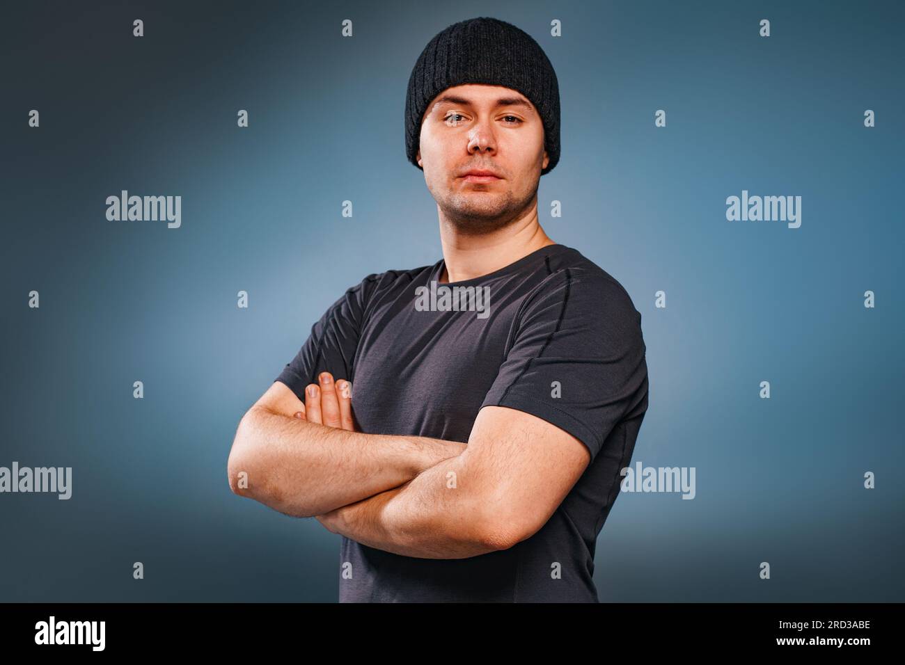 Giovane uomo forte e bello che posa su sfondo grigio Foto Stock