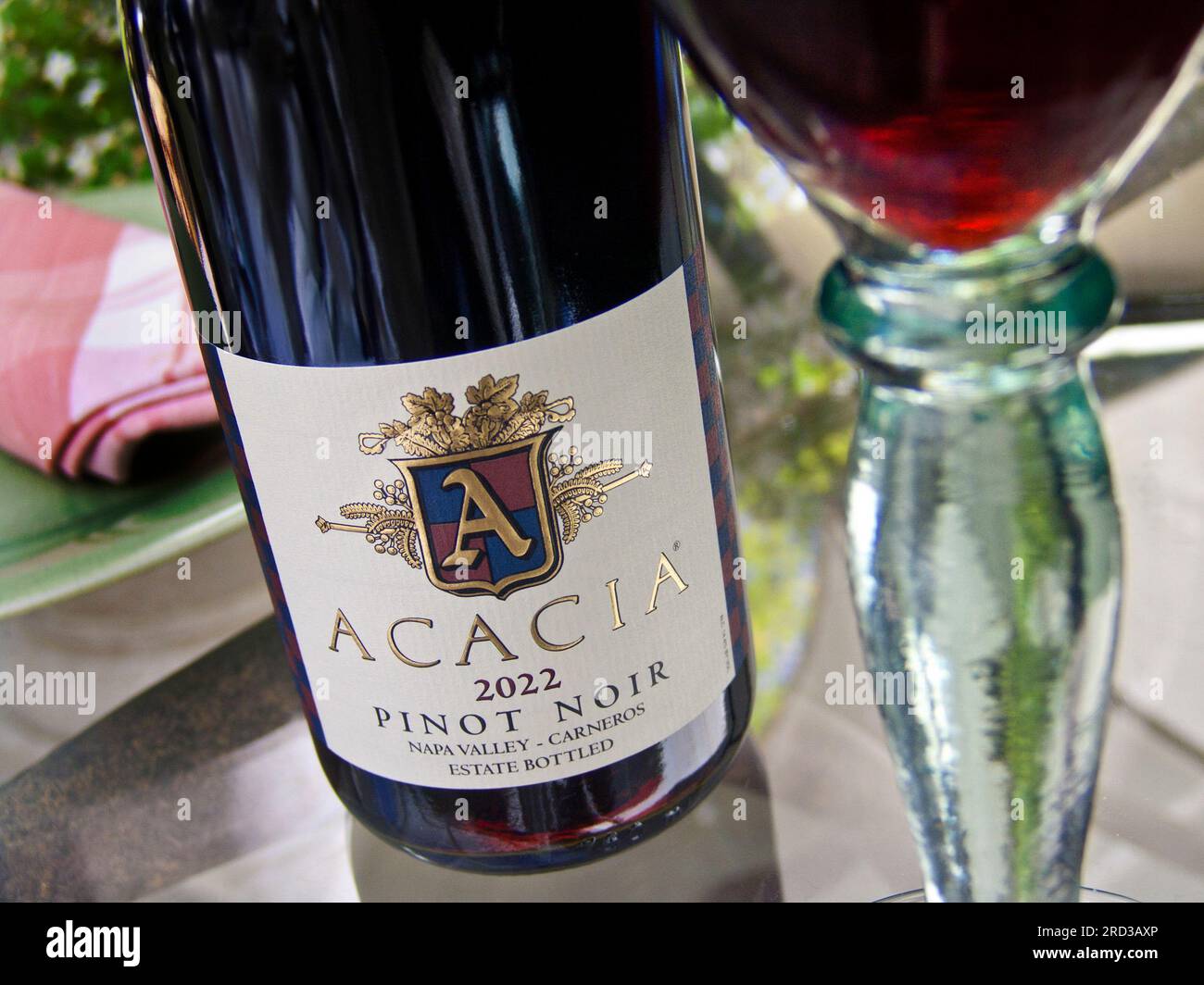 CALIFORNIA NAPA VALLEY Acacia 2022 bottiglia di Pinot Nero e bicchiere di vino rosso Carneros su un tavolo in vetro floreale all'aperto nella Napa Valley California USA Foto Stock