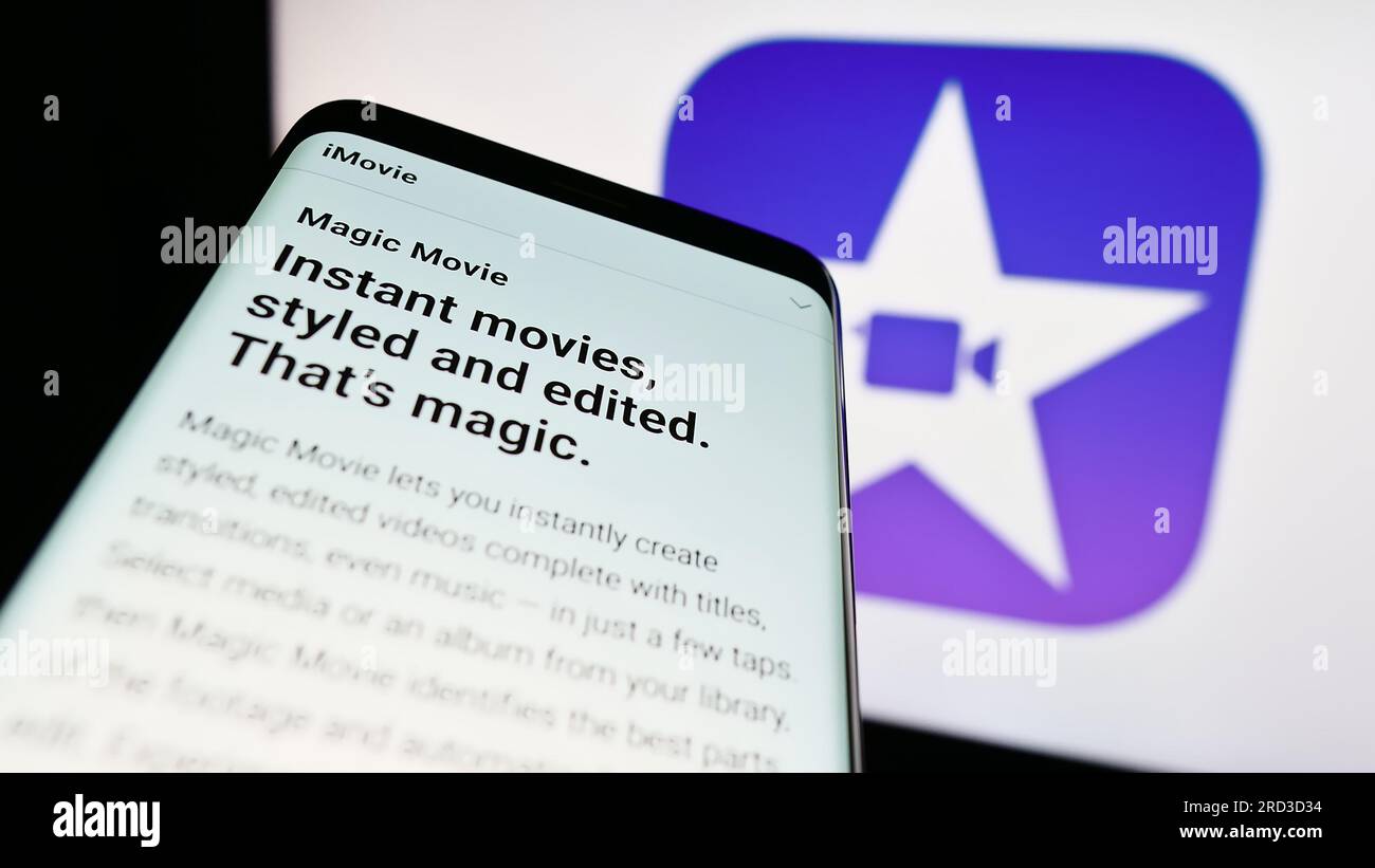 Smartphone con sito Web del software di editing video iMovie (Apple Inc.) sullo schermo davanti al logo aziendale. Mettere a fuoco in alto a sinistra sul display del telefono. Foto Stock
