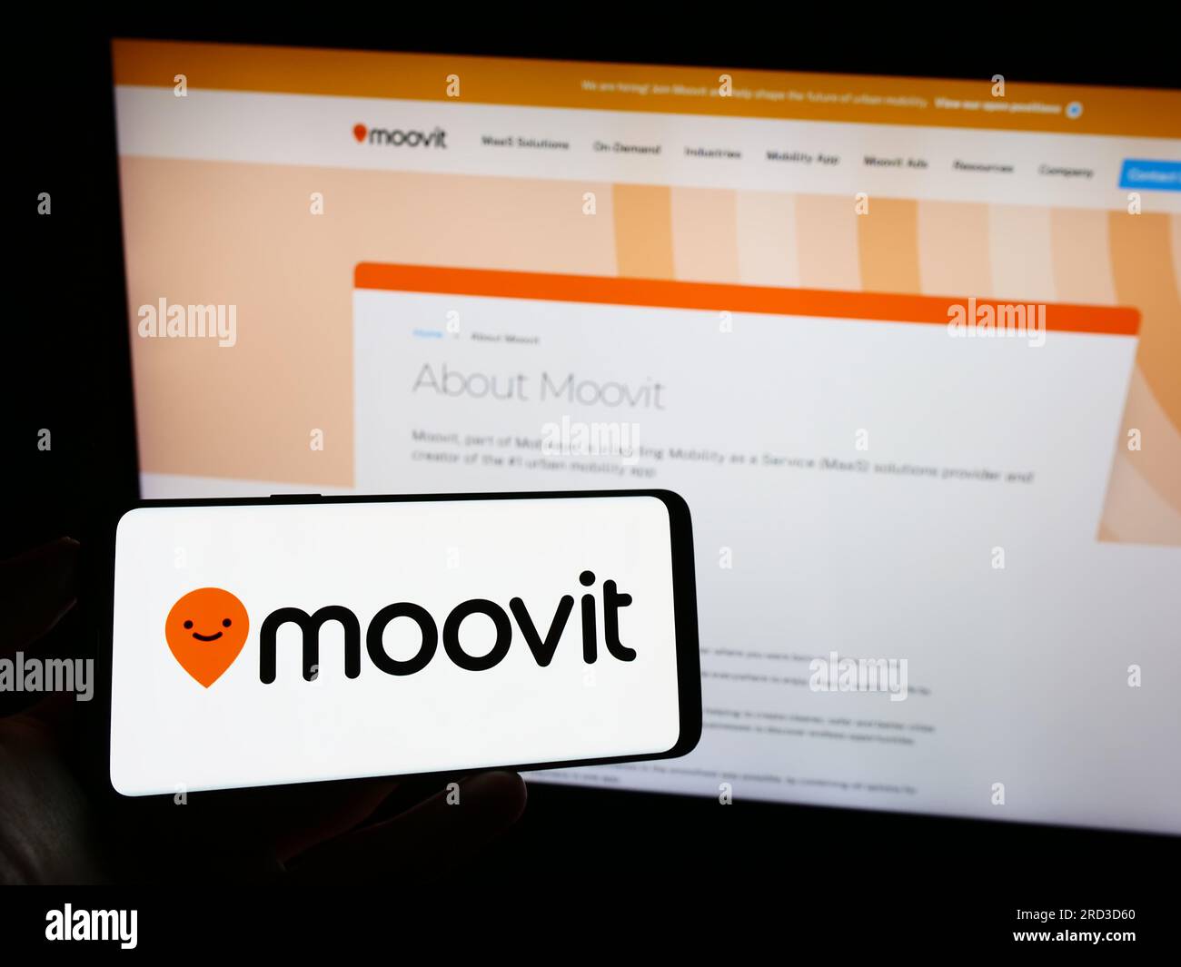 Persona che tiene il cellulare con il logo della società di mobilità israeliana Moovit Inc. Sullo schermo di fronte alla pagina Web aziendale. Concentrarsi sul display del telefono. Foto Stock