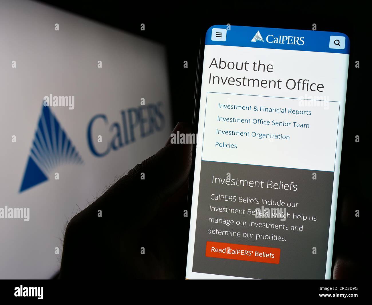 Persona in possesso di cellulare con pagina Web del sistema di pensionamento californiano CalPERS sullo schermo davanti al logo. Concentrarsi sul centro del display del telefono. Foto Stock