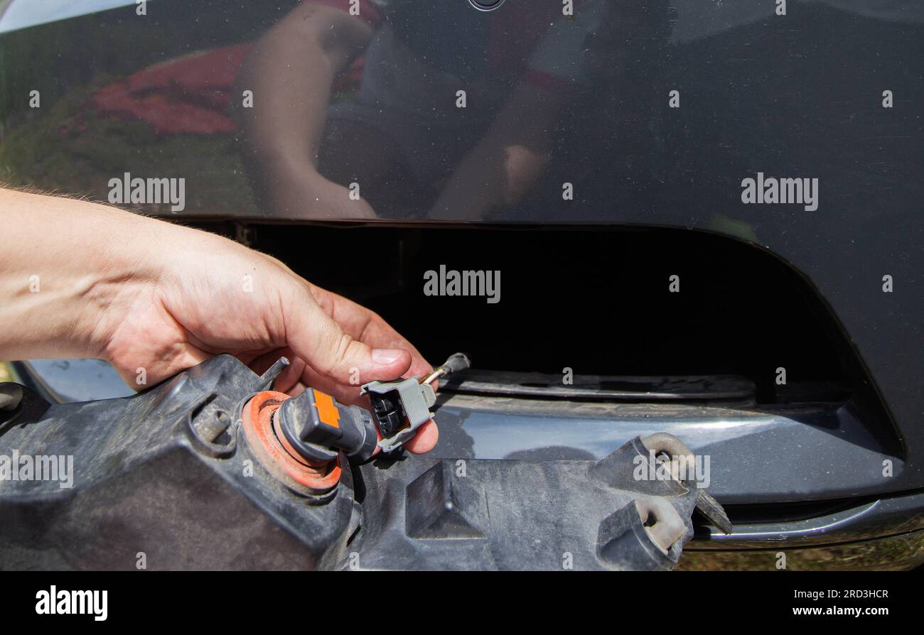 Per sostituire la lampadina della luce, scollegare il connettore elettrico del fendinebbia di un'autovettura. Foto Stock