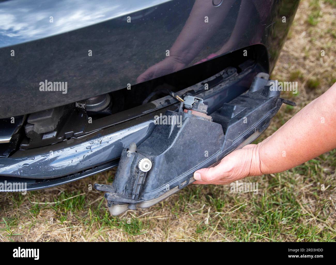 Smontaggio e rimozione del fendinebbia da una vettura per sostituire una lampadina bruciata. Foto Stock