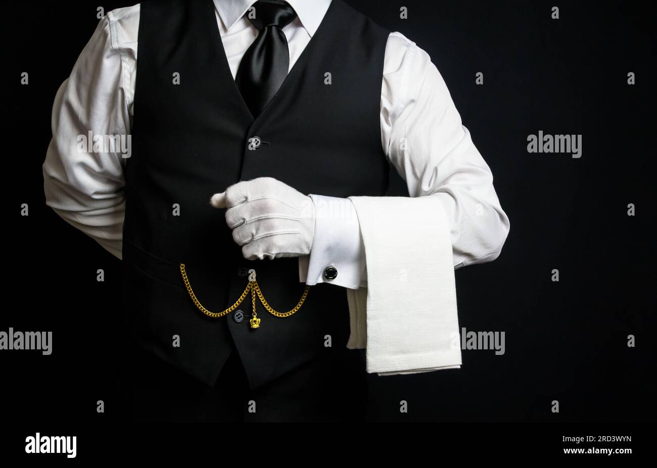 Ritratto di un elegante maggiordomo o cameriere con giubbotto nero e guanti bianchi desiderosi di essere d'aiuto. Foto Stock