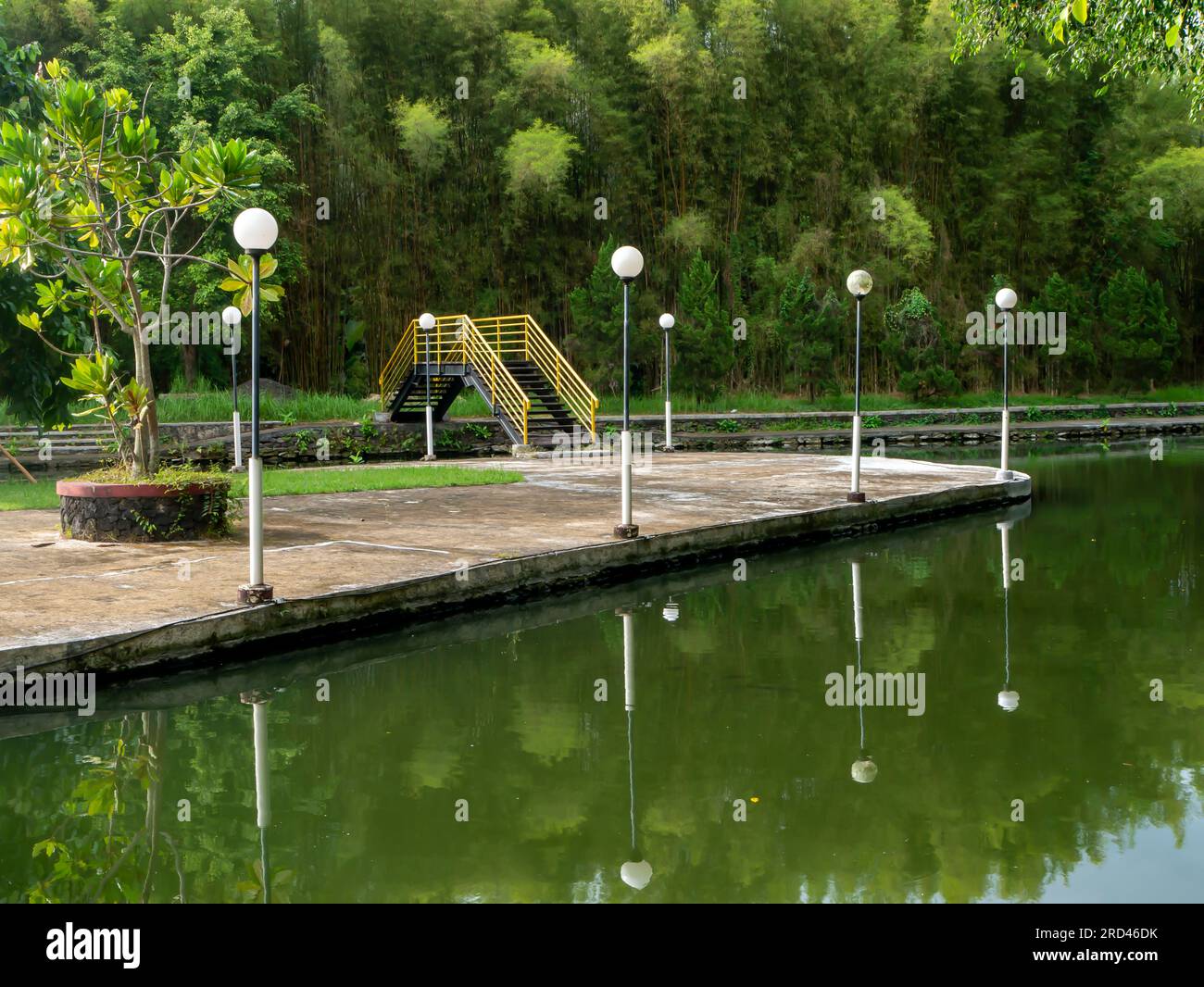 Vista panoramica di uno stagno e di un ponte giallo nel parco cittadino di Yogyakarta, Indonesia. Sfondo naturale. Foto Stock