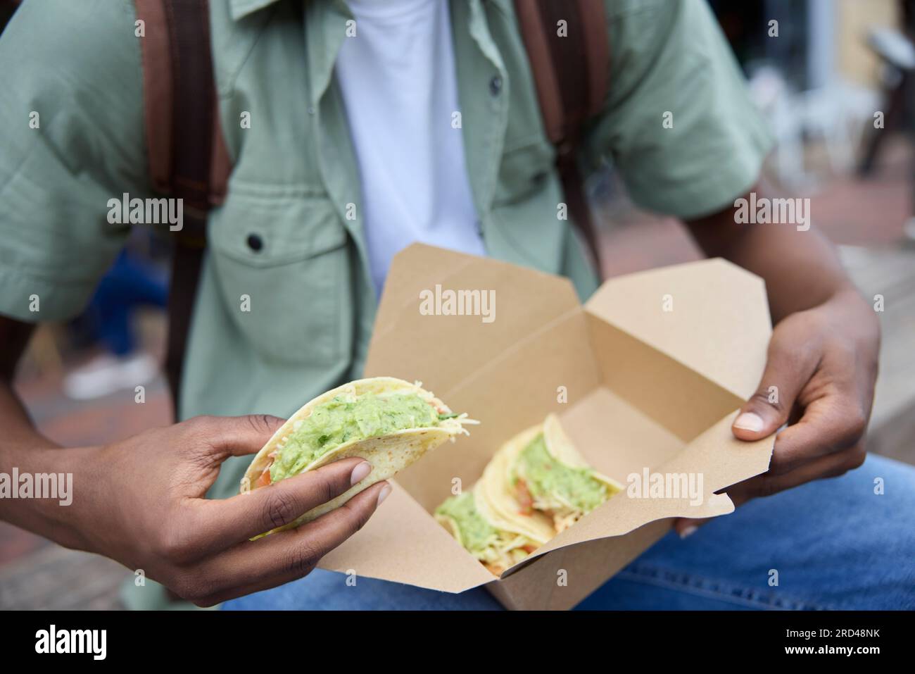 Primo piano di Young Man Eating Taco al Outdoor Street Food Stall Foto Stock