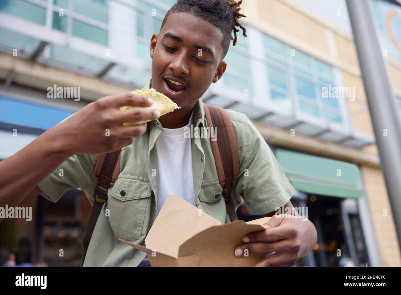 Young Man che mangia Taco all'Outdoor Street Food Stall Foto Stock