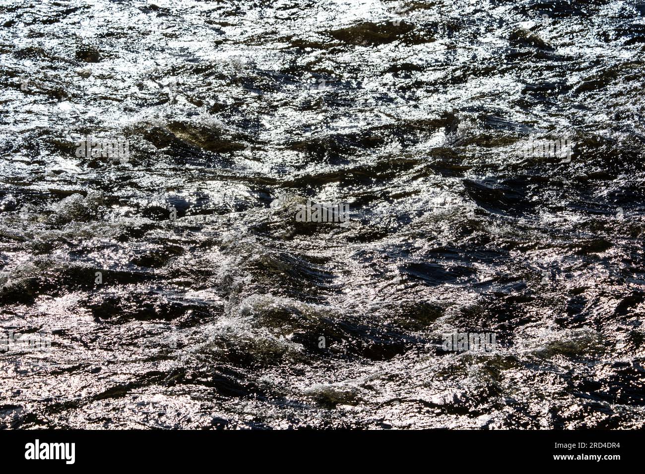 Onde astratte e increspature sotto una luce molto luminosa sulla superficie dell'acqua Foto Stock