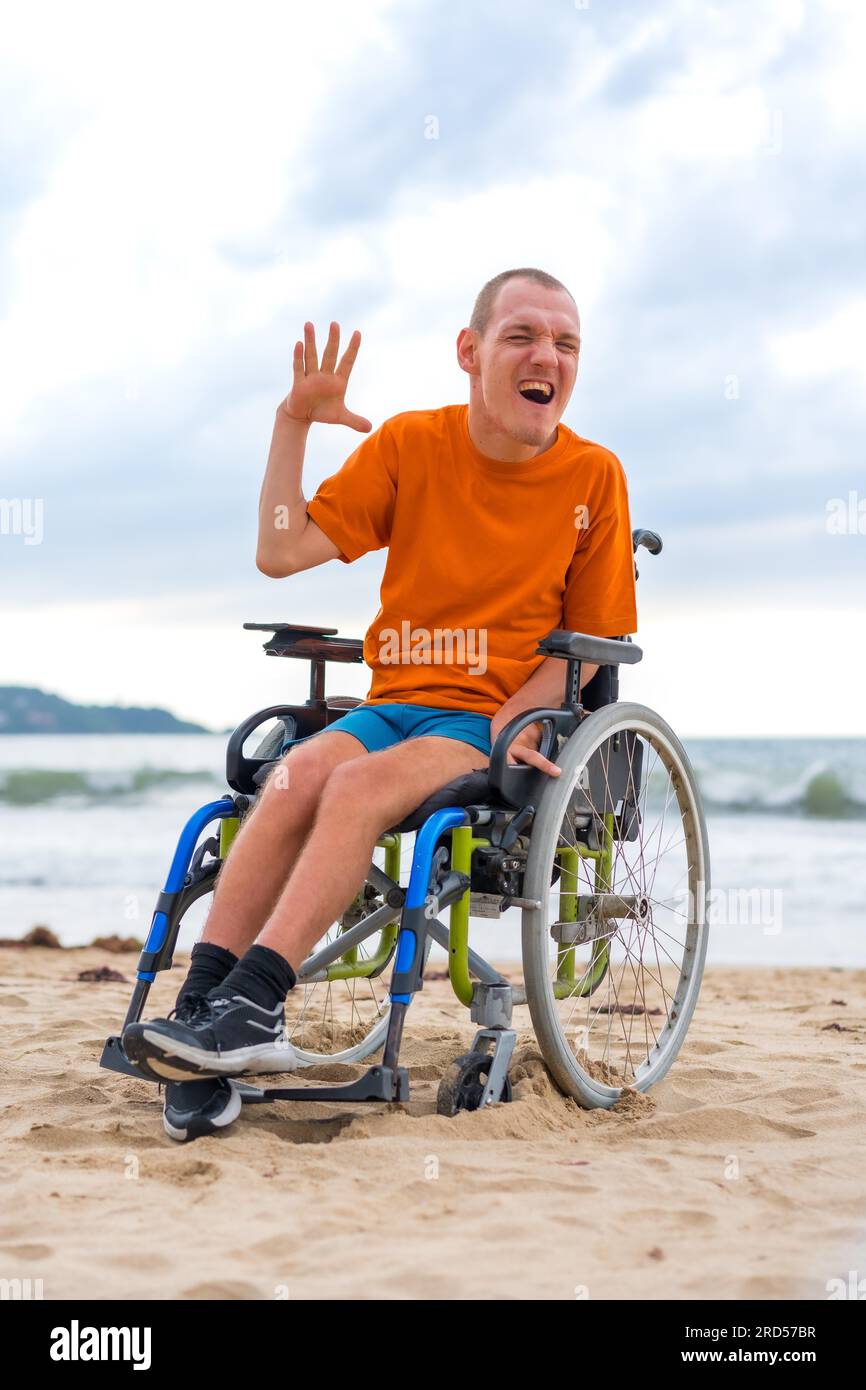 Una persona con disabilità in sedia a rotelle sulla spiaggia in estate Foto Stock