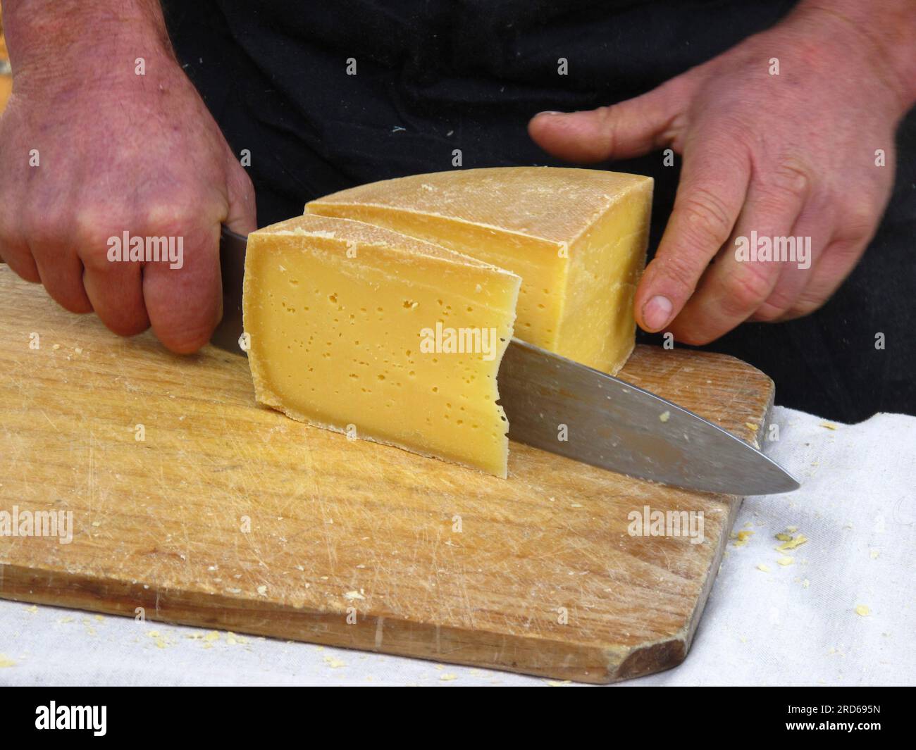 Porta-stalle del mercato della Tasmania e caseificio che affetta un formaggio a cheddar per un cliente Foto Stock