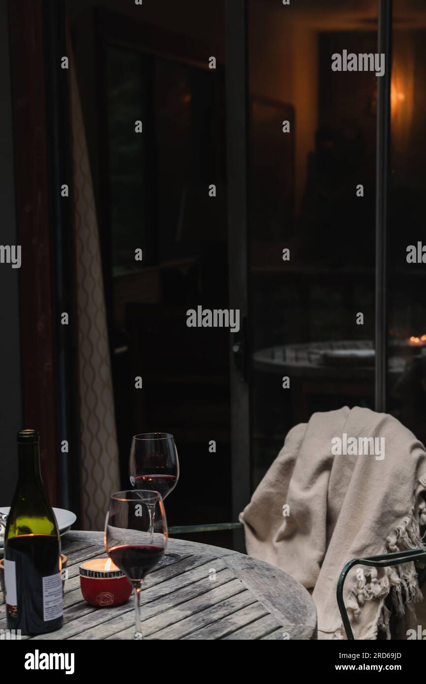 Vino rosso e due bicchieri sul patio, atmosfera accogliente, vita in cabina Foto Stock