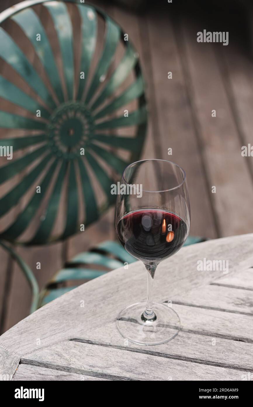 Bicchiere di vino rosso in piedi sul tavolo di legno sul patio, atmosfera intima Foto Stock