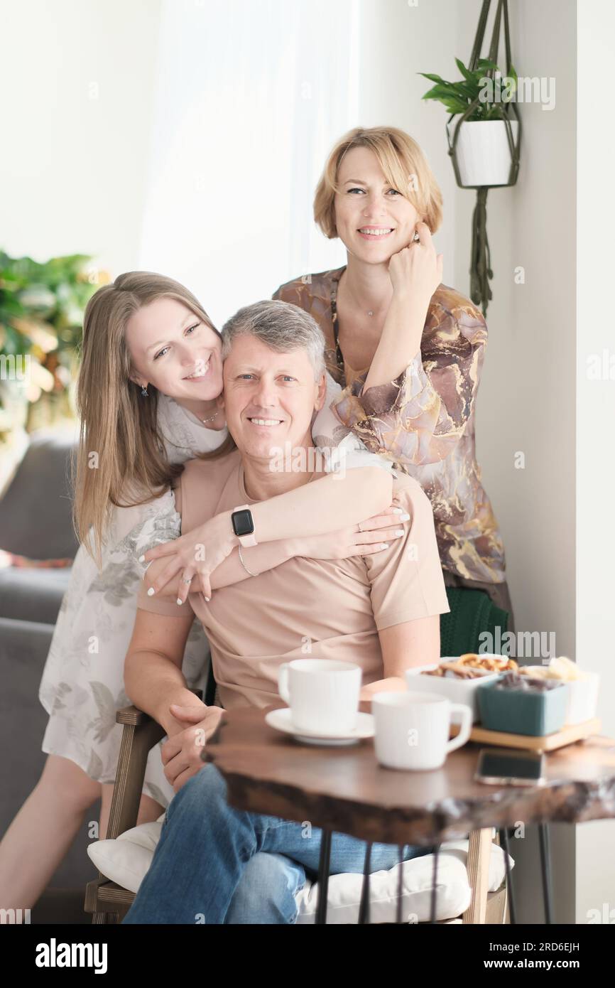 ritratta figlia adulta sorridente che abbraccia il padre più vecchio da dietro, guarda la macchina fotografica, due generazioni, bella giovane donna che abbraccia un uomo maturo, posa per una foto con i genitori Foto Stock