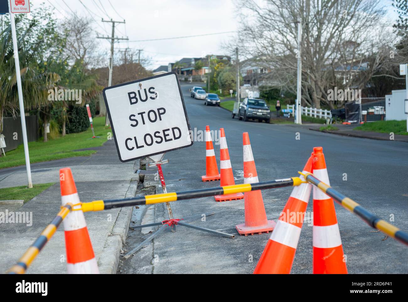 Alla fermata DELL'AUTOBUS C'È un cartello di CHIUSURA tra i coni del traffico arancione. Auto e persone per strada irriconoscibili. Riparazione di strade danneggiate da inondazioni ad Auckla Foto Stock