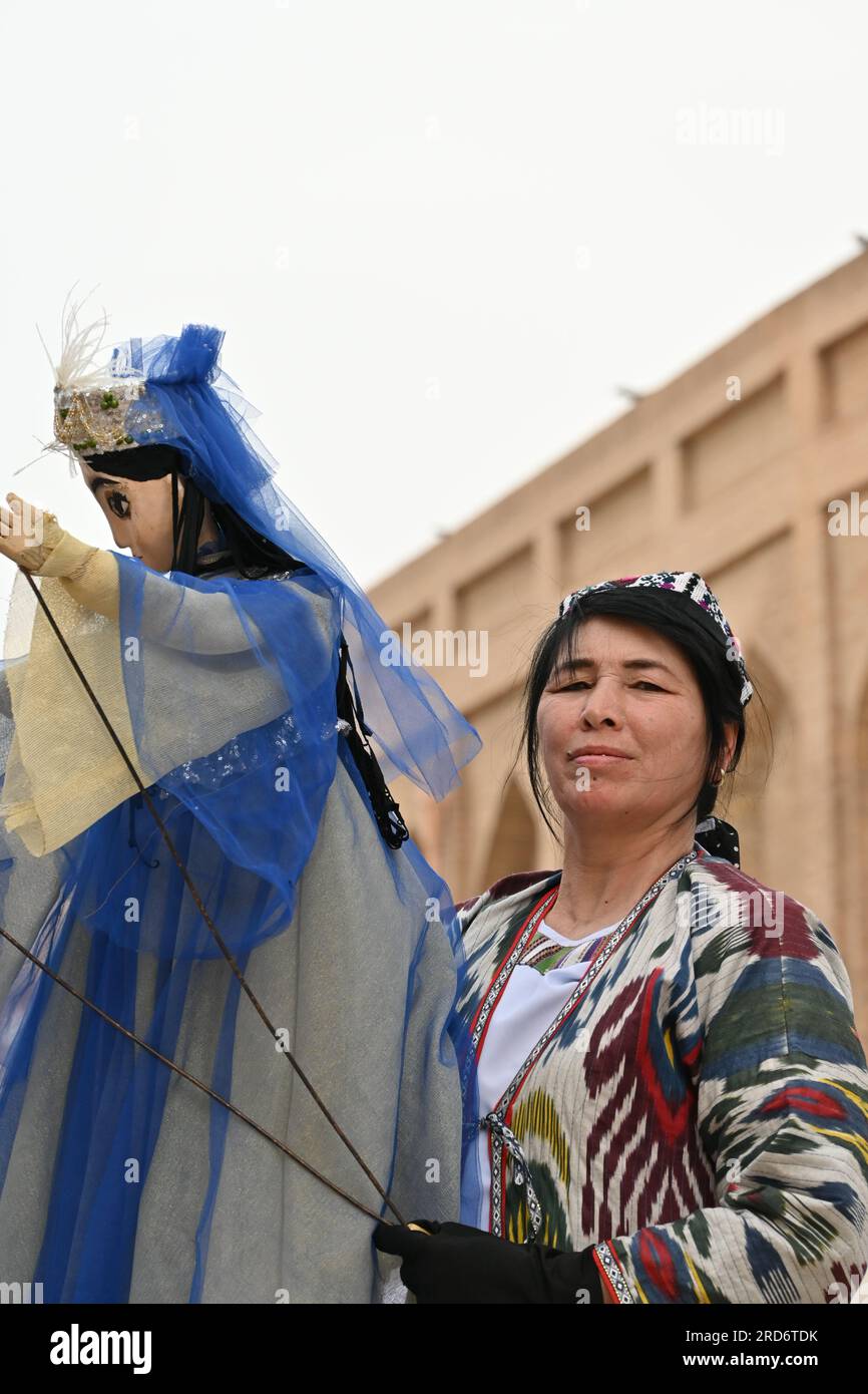 Donna uzbeka che tiene un burattino durante una performance per strada a Khiva, Uzbekistan Foto Stock