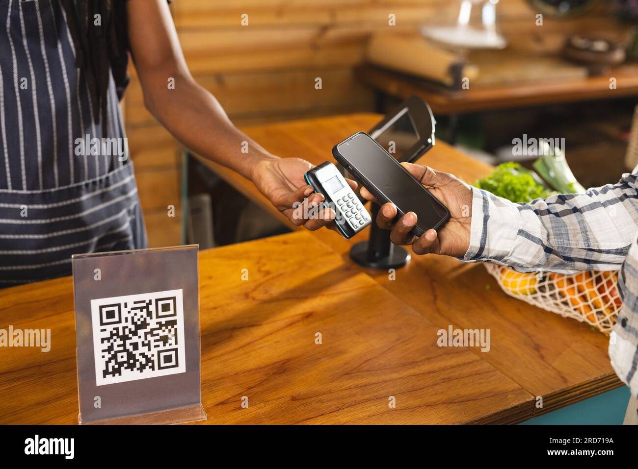 Metà della senior afro-americana uomo pagando con smartphone a cibo salutare negozio di alimentari biologico Foto Stock