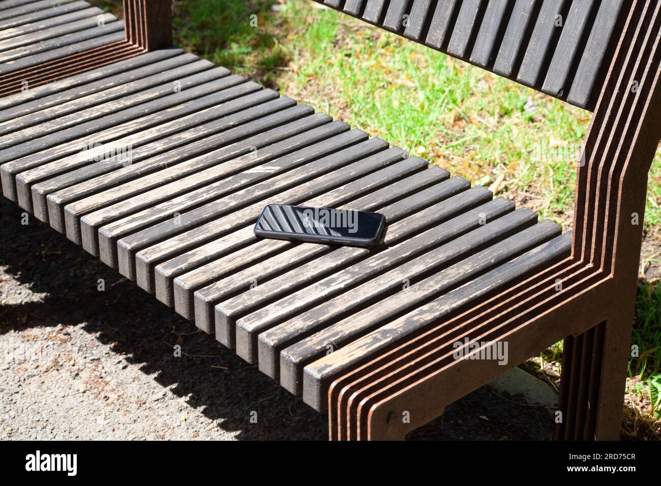 Smartphone dimenticato sulla panca di legno nel parco cittadino. ho perso il telefono nel parco Foto Stock