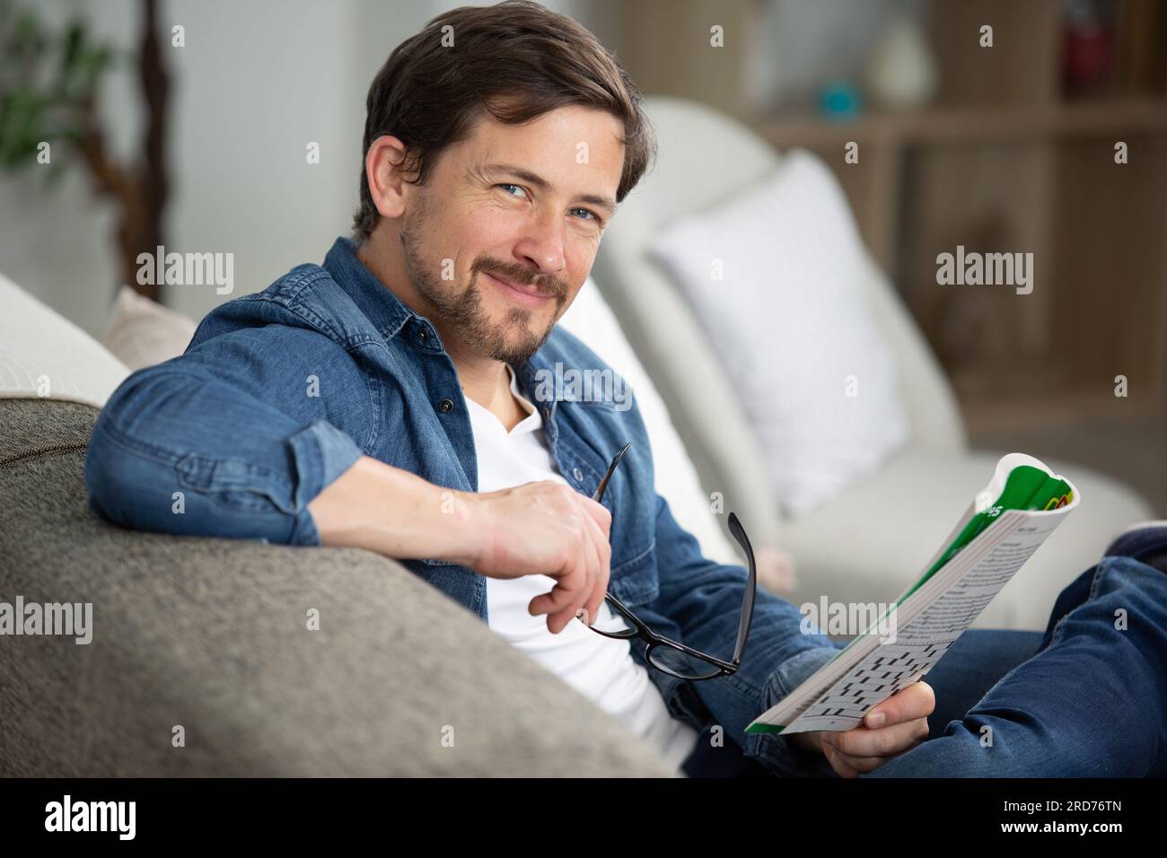 giovane uomo seduto facendo un puzzle crossword Foto Stock