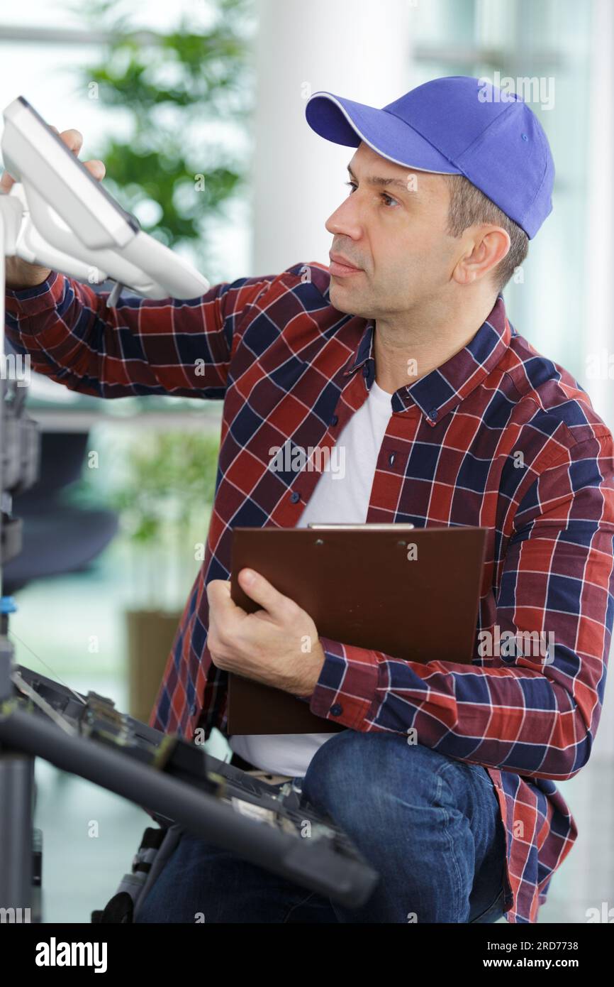 L'uomo tecnico riparare una stampante al posto di business al lavoro Foto Stock