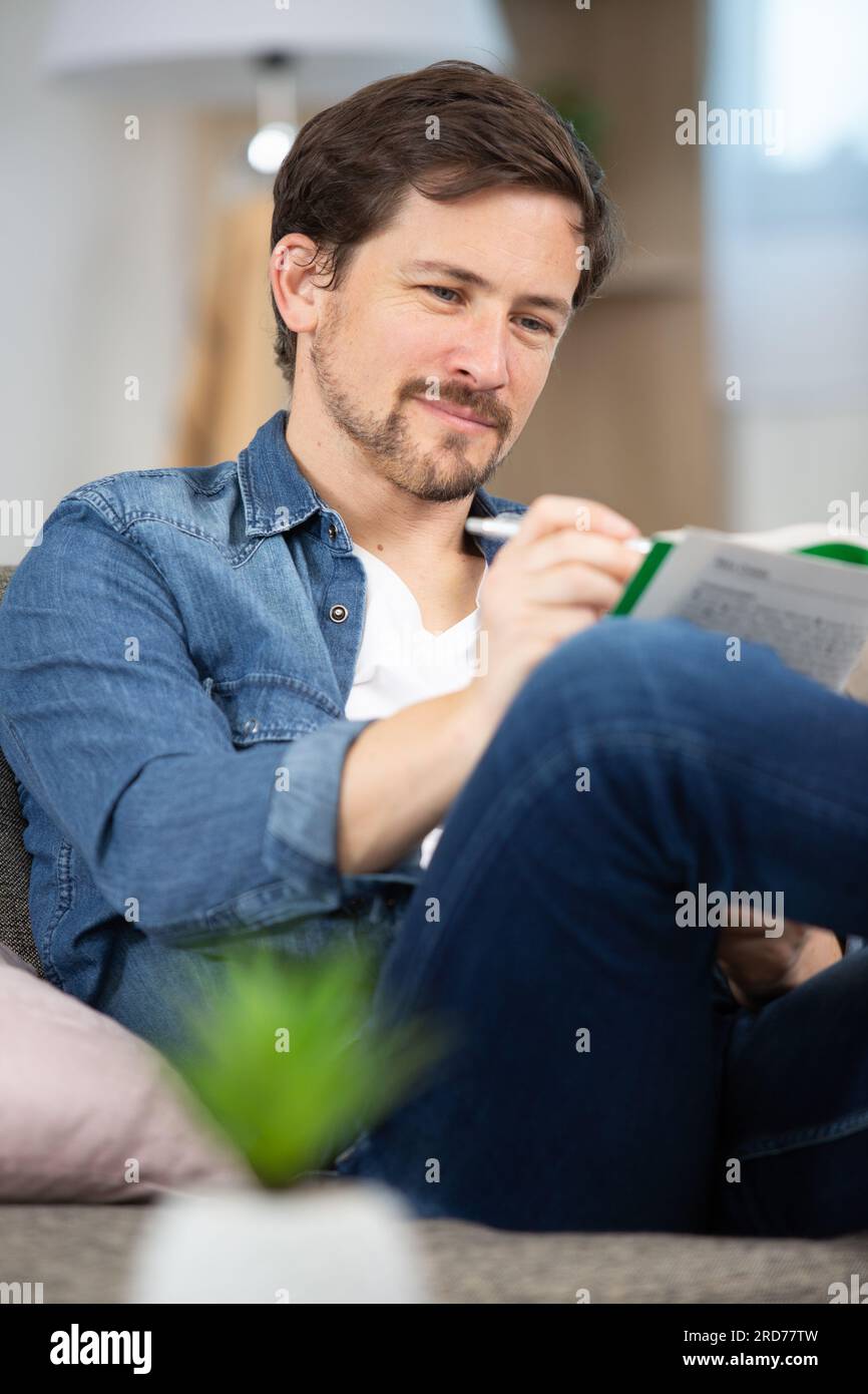 giovane seduto a fare un puzzle con parole incrociate Foto Stock