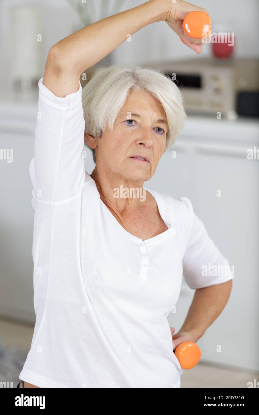 piacevole donna anziana che solleva i manubri Foto Stock