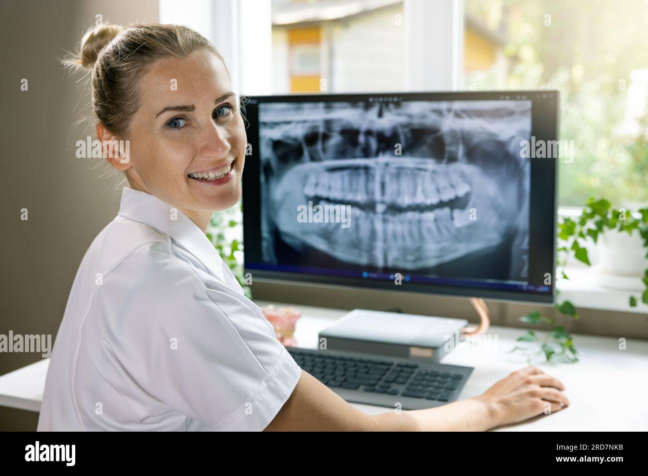dentista sorridente che lavora con l'immagine a raggi x dentale sul computer negli studi clinici Foto Stock